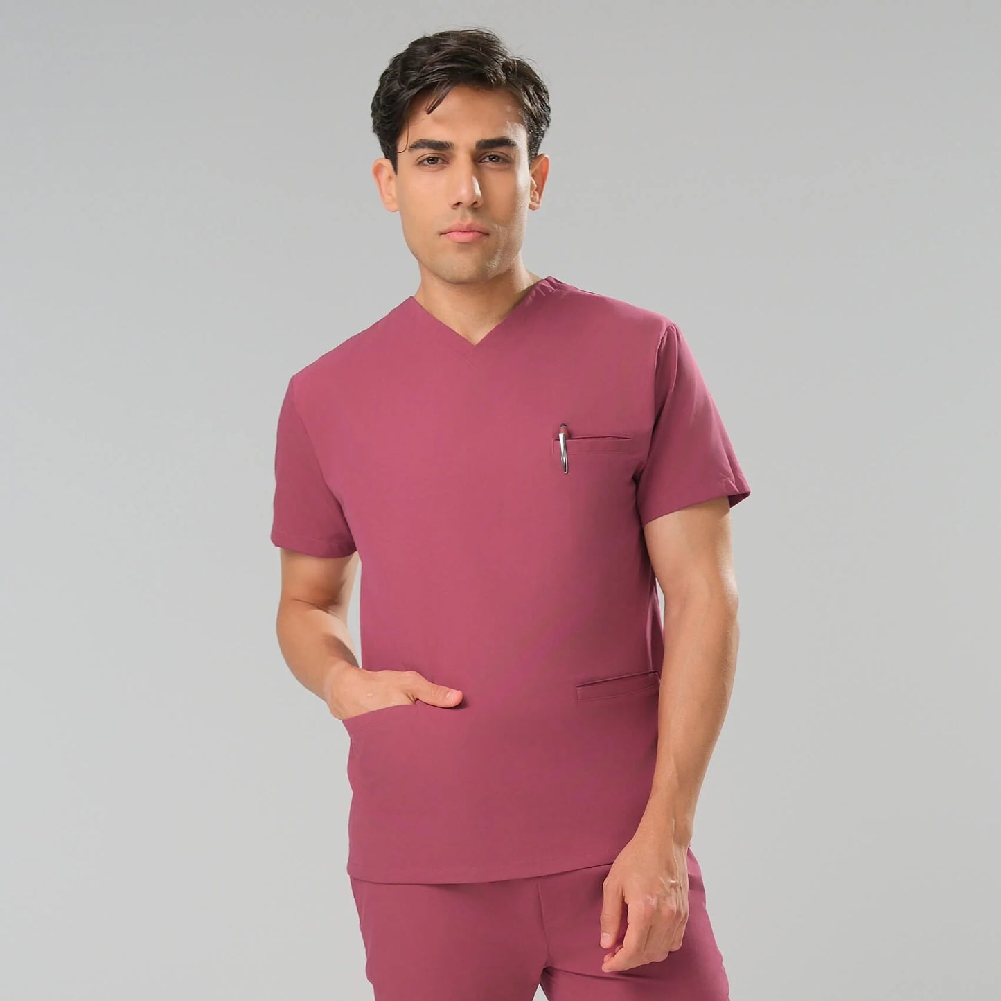 Man wearing a red scrub set against a grey background