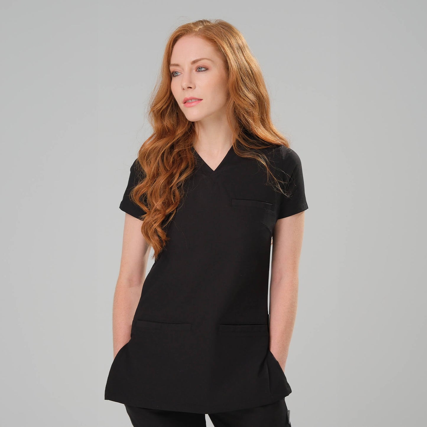 Woman wearing a black scrub top against a grey background