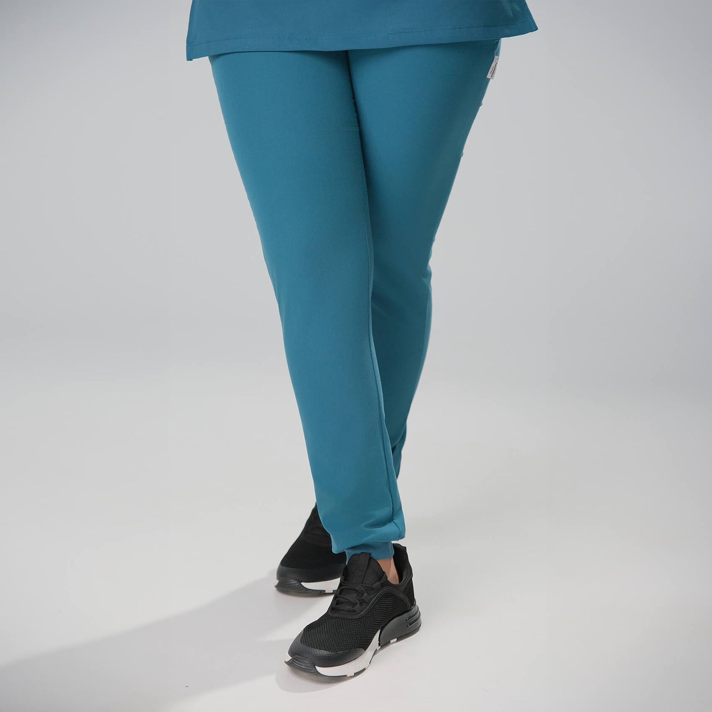Woman wearing green scrub joggers  on a white background