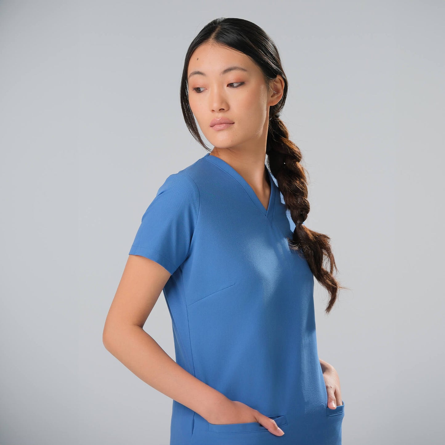 Woman wearing a light blue scrub top against a grey background