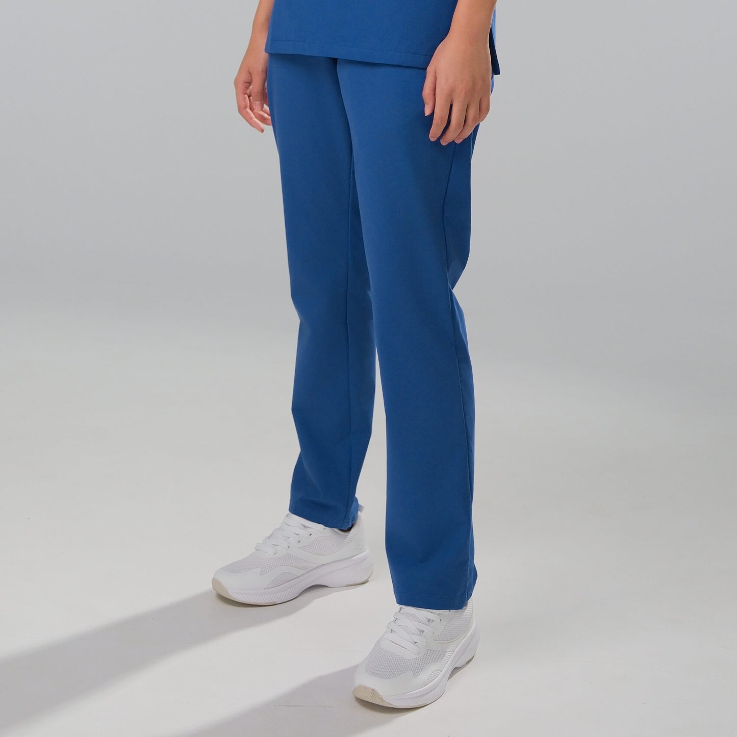 Woman wearing royal blue scrub trousers with white trainers